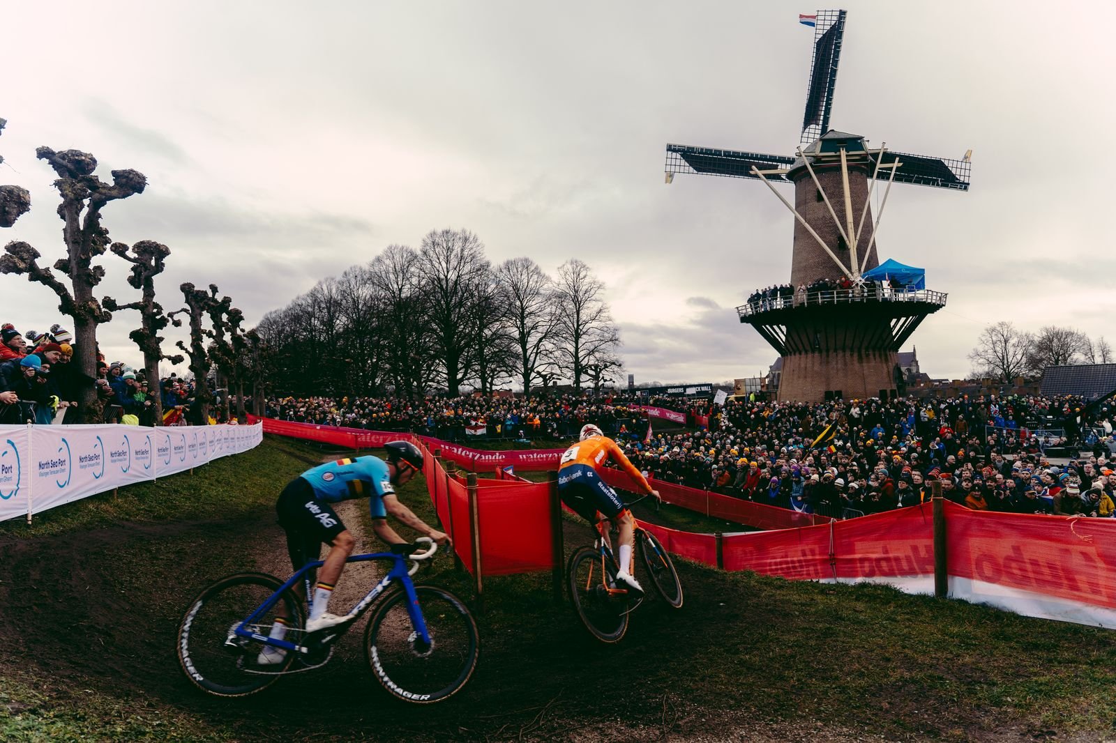 Deux coureurs dans un virage devant le moulin